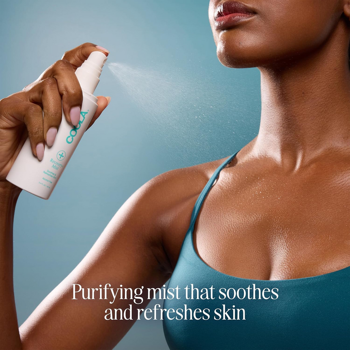 Woman using COOLA Recovery+ Mist  on her skin with a blue background