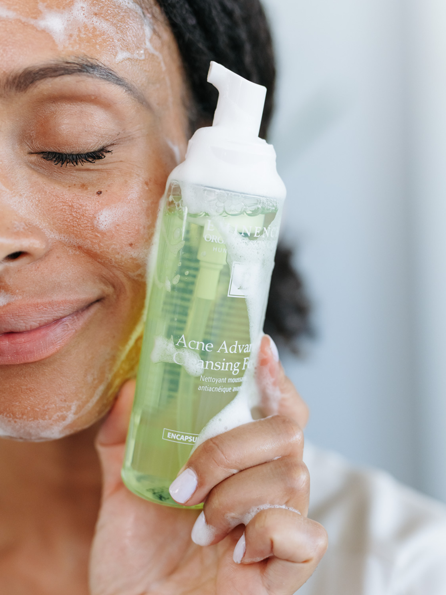 woman using Eminence Organics Acne Advanced Cleansing Foam on her face