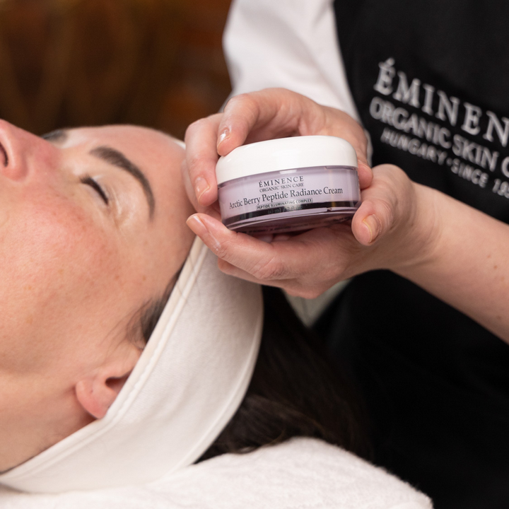 Person applying Eminence Organics Arctic Berry Peptide Radiance Cream to a client&