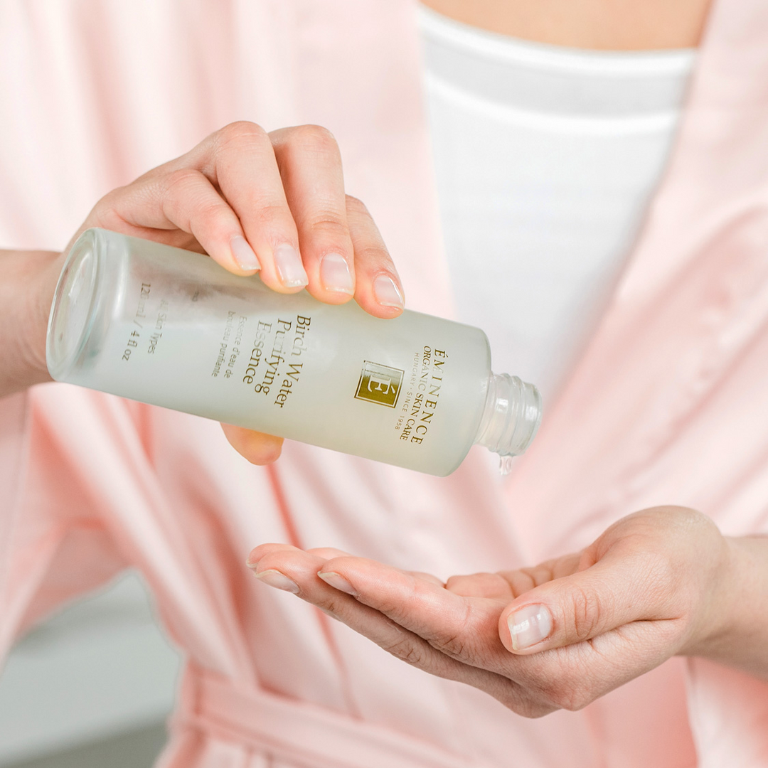 woman pouring Eminence Organics Birch Water Purifying Essence into her hand