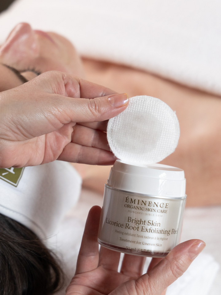 Person holding Eminence Organics Bright Skin Licorice Root Exfoliating Peel with a cotton pad