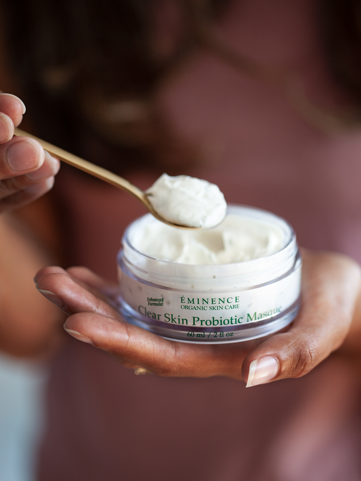 Person holding a jar of Eminence Organics Clear Skin Probiotic Mask with a spoonful above it.