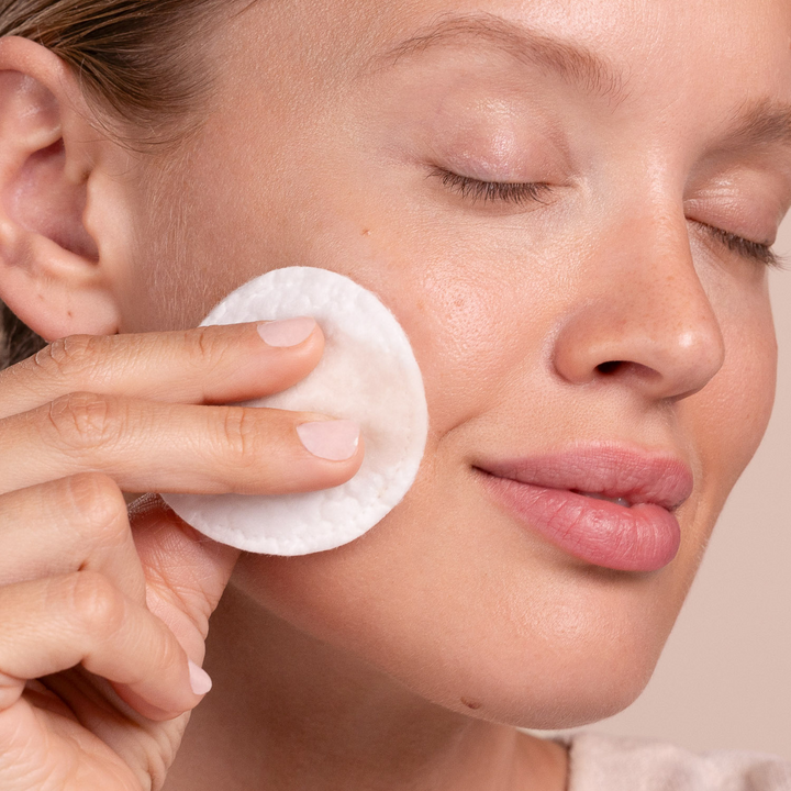 Person using Eminence Organics Clear Skin Willow Bark Exfoliating Peel on their face with a neutral background