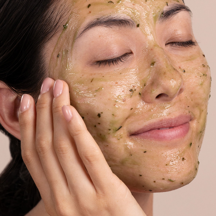 Woman applying Eminence Organics Eight Greens Phyto Masque - Not Hot with green herbs on her face