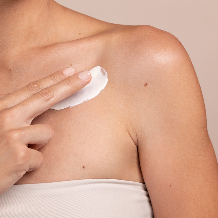 woman applying Eminence Organics Lilikoi Mineral Defense Sport Sunscreen SPF 30 on her shoulder