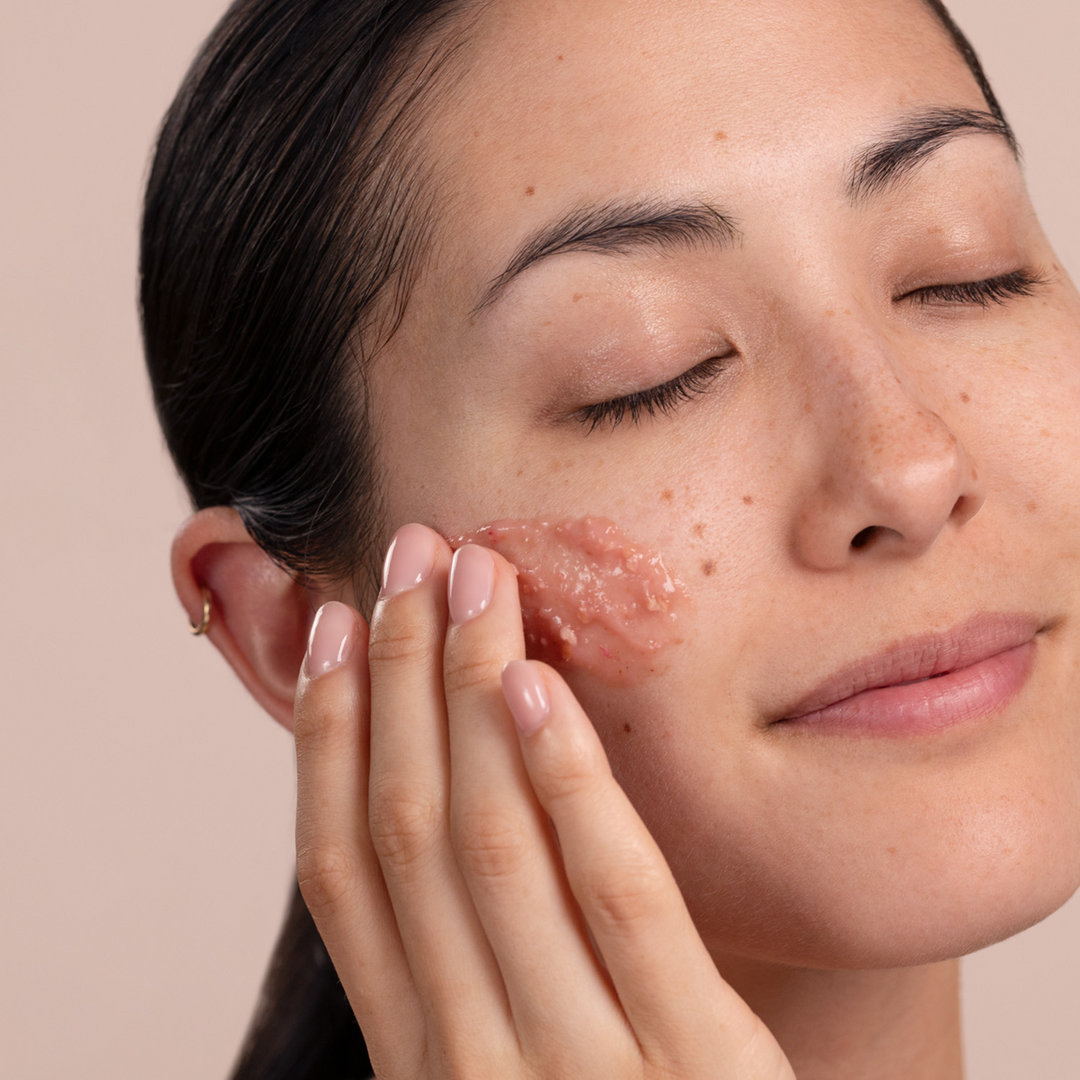 Woman applying Eminence-Organics-Radish-Seed-Refining-Peel-model to her face with a neutral background