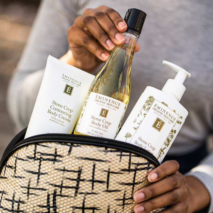 woman pulling Eminence Organics Stone Crop Body Oil from a bag