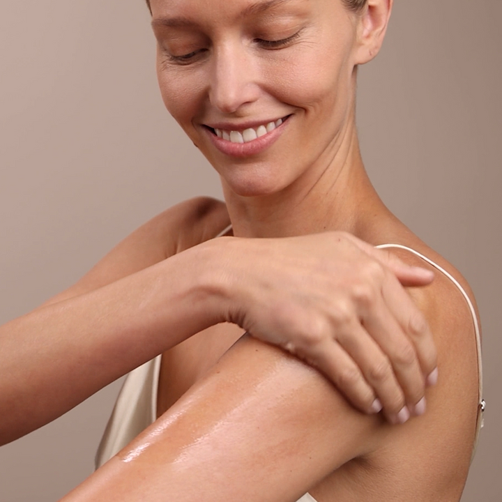 woman applying Eminence Organics Stone Crop Body Oil to her shoulder