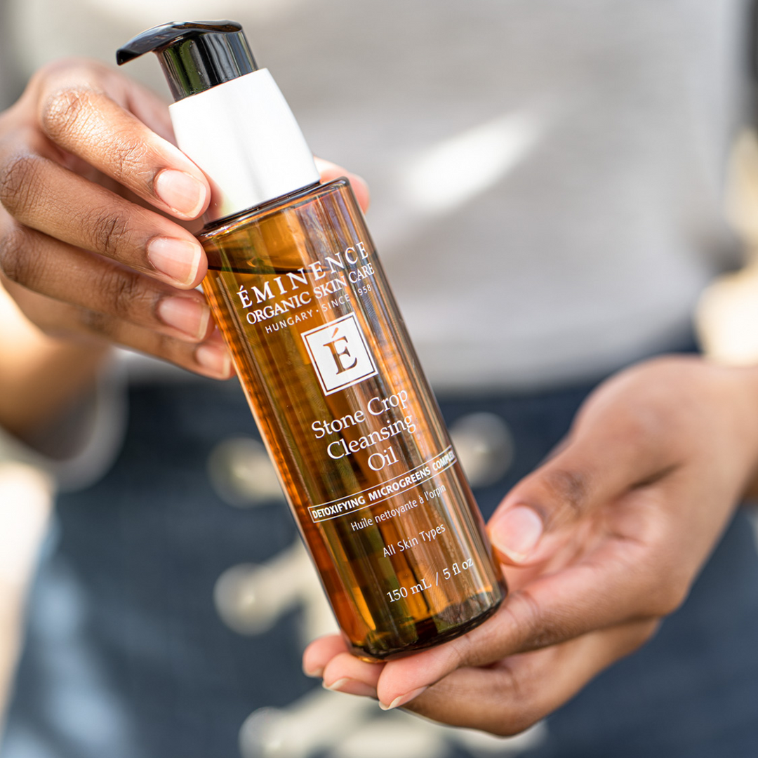Person holding a bottle of Eminence Organic Skincare Stone Crop Cleansing Oil.