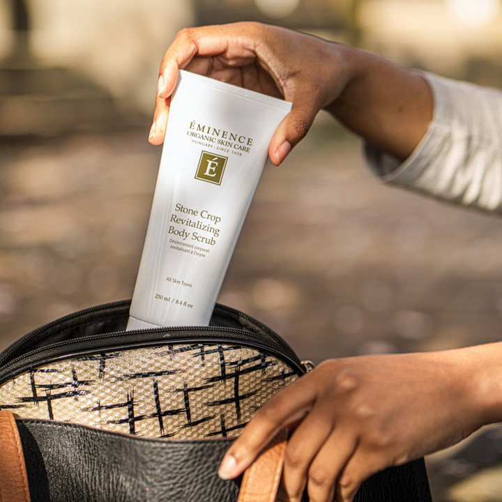 woman pulling Eminence Organics Stone Crop Revitalizing Body Scrub from her bag