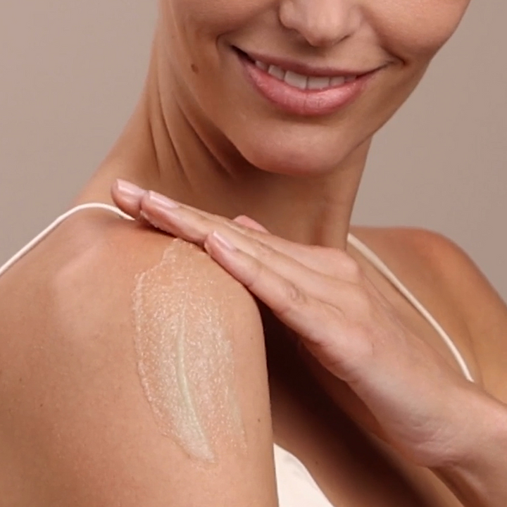 woman applying Eminence Organics Stone Crop Revitalizing Body Scrub on her shoulder
