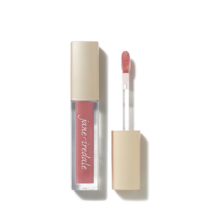A clear tube of Jane Iredale ColorLuxe High Impact Lip Glaze amour with a nude beige cap, shown next to its applicator wand with a pink-peach glittery tip on a white background.