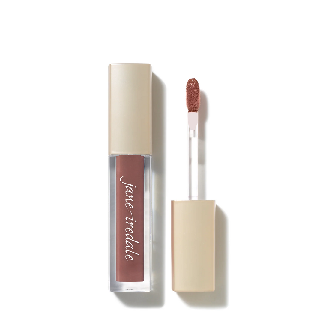 A clear tube of Jane Iredale ColorLuxe High Impact Lip Glaze pink suede with a beige cap, shown next to its applicator wand with a nude pink-brown lip color tip, on a white background.