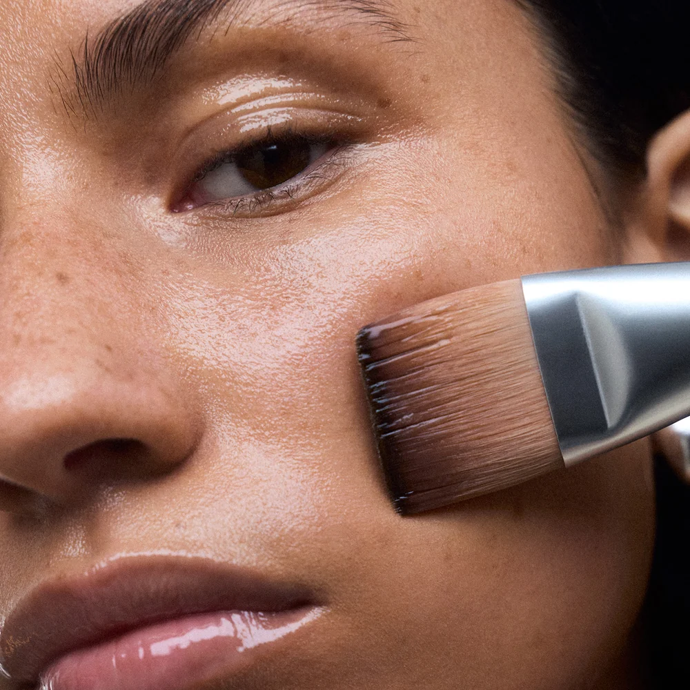 Close-up of a person applying product with NuFACE Clean Sweep Applicator Brush to their face.