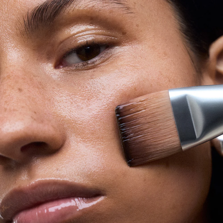 Close-up of a person applying product with NuFACE Clean Sweep Applicator Brush to their face.