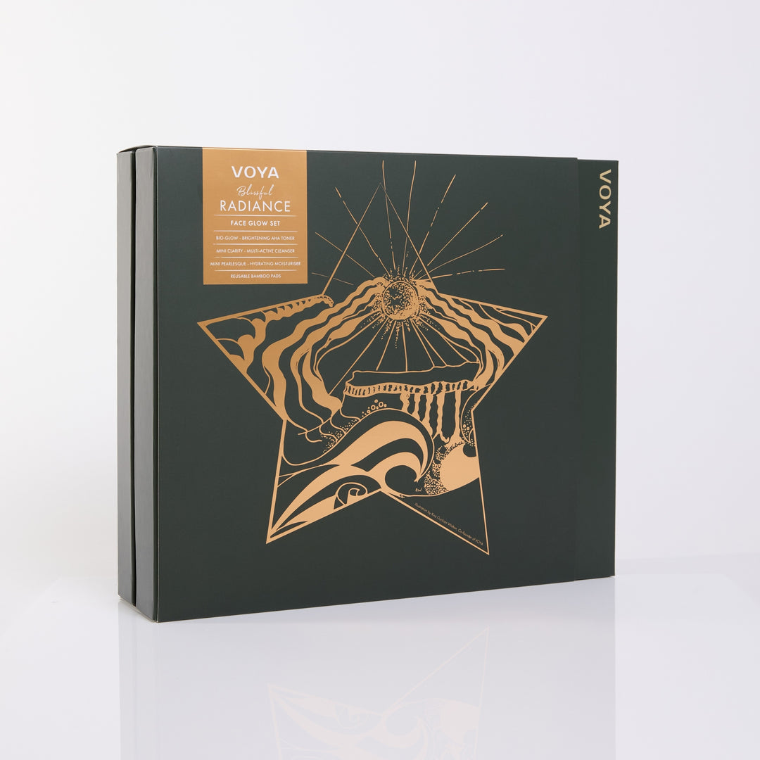 VOYA Blissful Radiance gift box featuring a gold star with coastal illustrations on dark green packaging.
