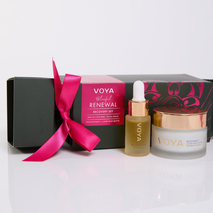 Close-up of VOYA My Little Hero facial serum and Buoyancy body butter beside the pink-ribboned Blissful Renewal gift box.
