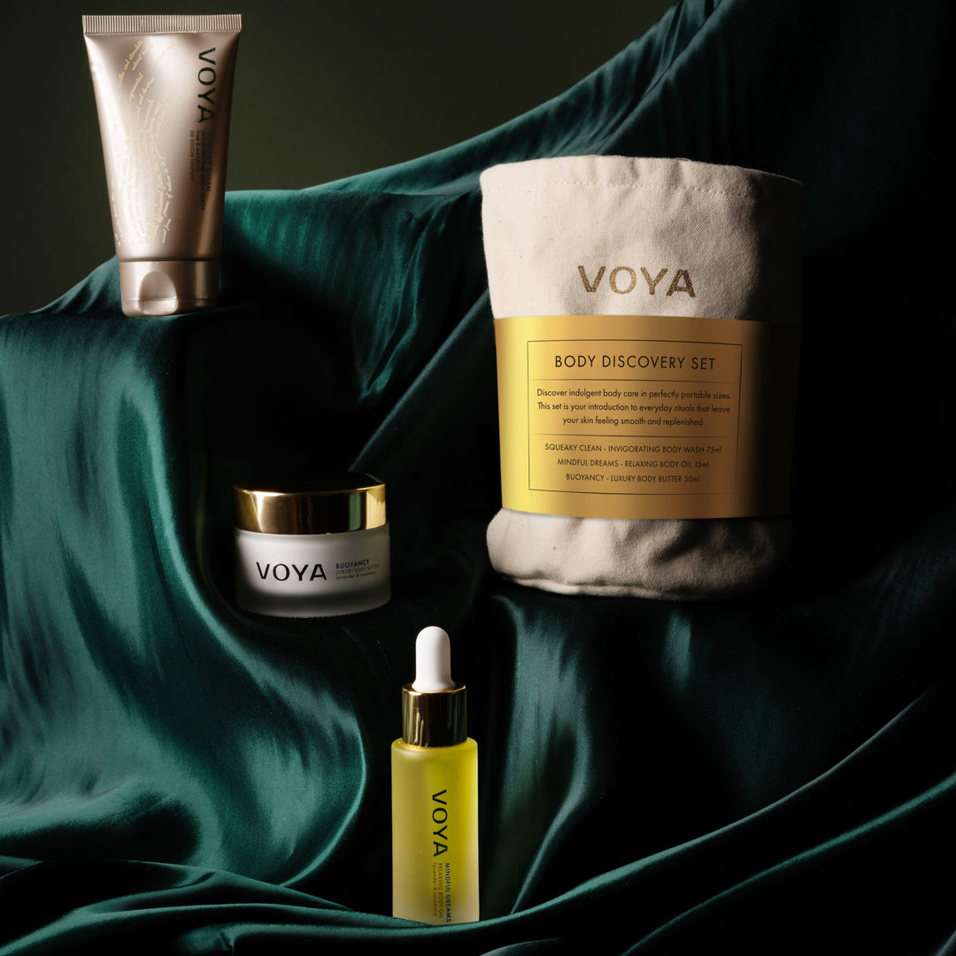 VOYA Body Discovery Set on a dark green fabric background