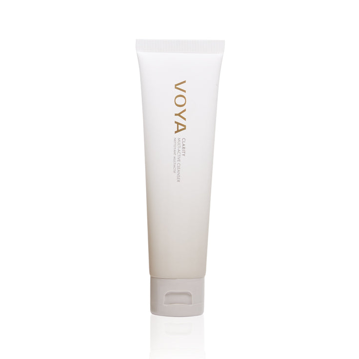 A white squeeze tube of VOYA Clarity: Multi-Active Cleanser with gold lettering, standing upright on a clean white background with a subtle reflection.