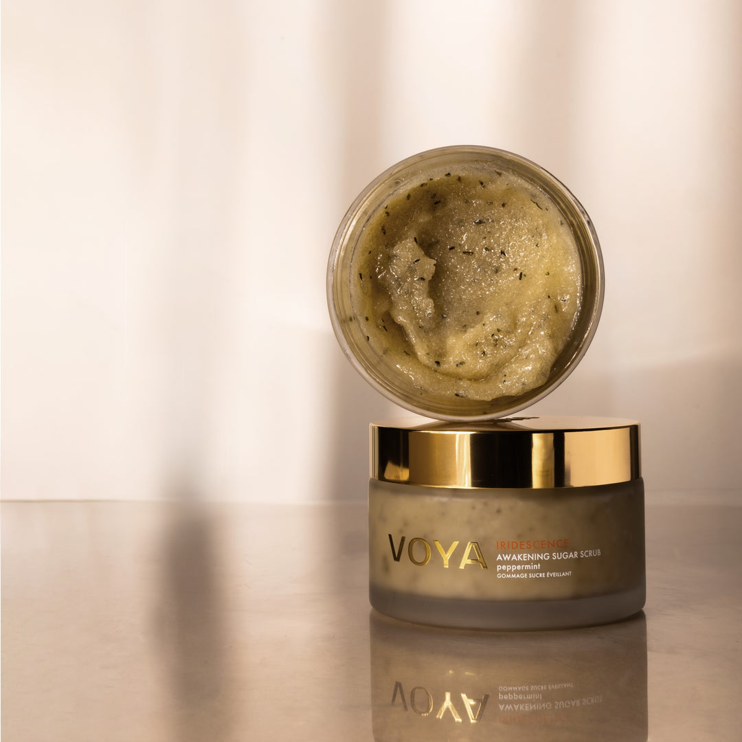 Open jar of VOYA Iridescence Awakening Sugar Scrub showing its grainy texture above a closed jar