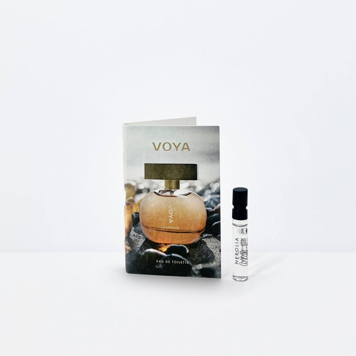 A small VOYA Nerolia - Eau de Toilette sample size with a printed perfume bottle image stands next to a clear glass sample vial with a black cap on a clean white background.
