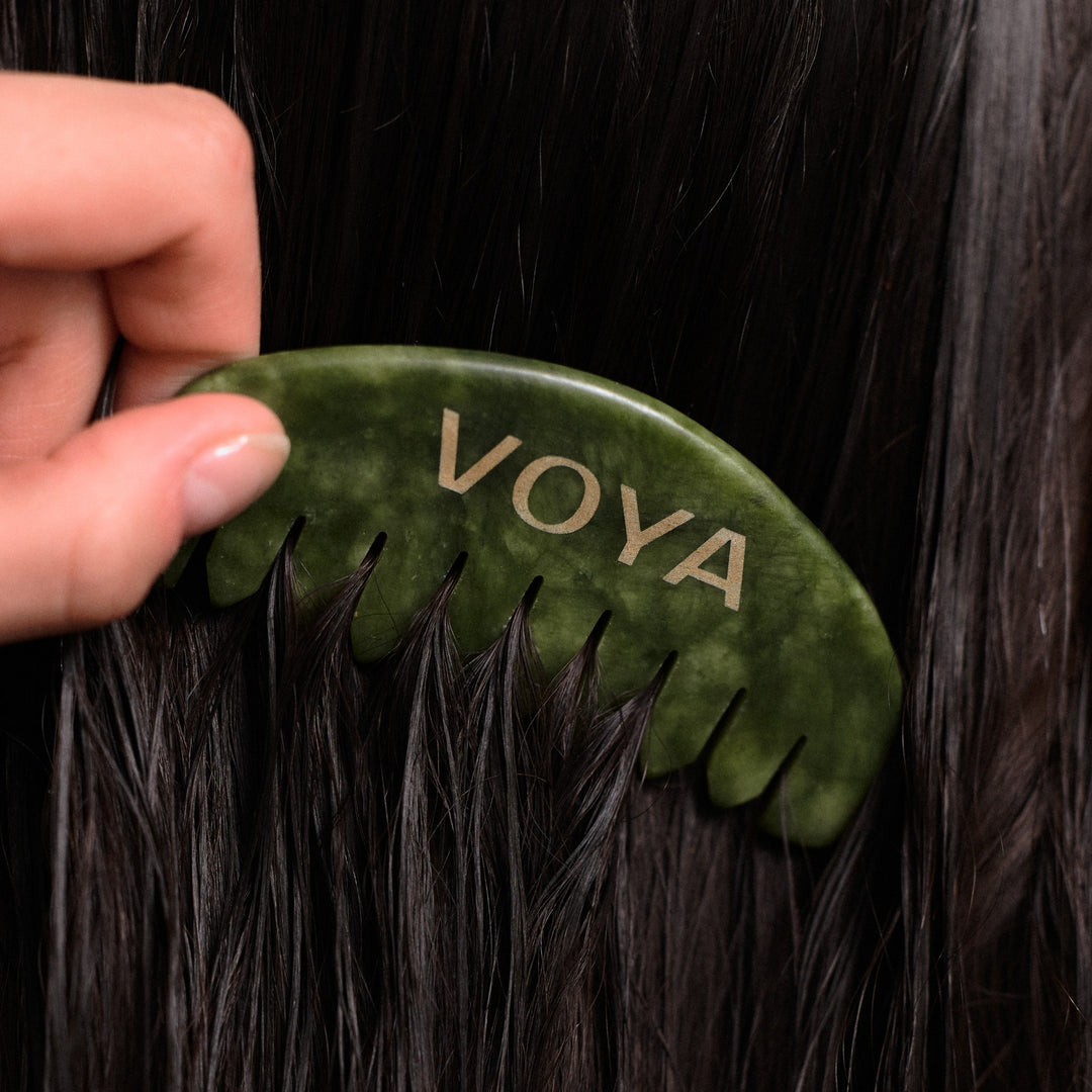 VOYA Resurge - Jade Gua Sha Comb being used on dark hair.