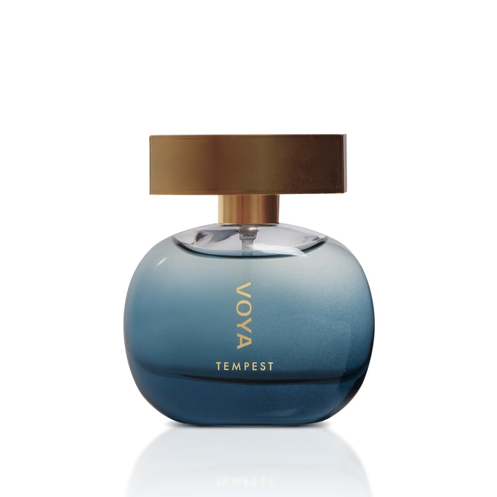 A round blue gradient glass perfume bottle with a metallic gold cap, featuring the text &